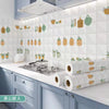 A kitchen splashback featuring decorative green and orange ceramic-style stickers on a white tile background.