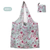 A light blue floral shopping tote bag with a pink and green pattern and an attached fabric carry pouch.