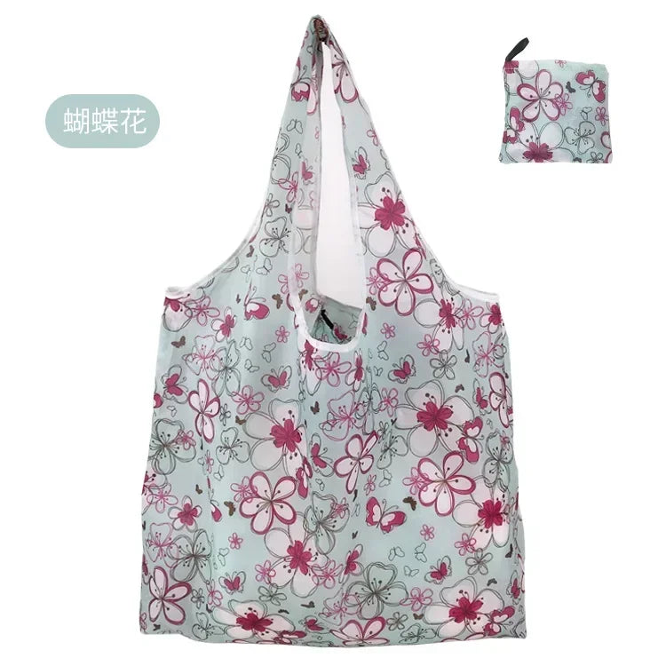 A light blue floral shopping tote bag with a pink and green pattern and an attached fabric carry pouch.