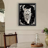A framed piece of art featuring a cat silhouette outlined in white beads and pearls against a black background.