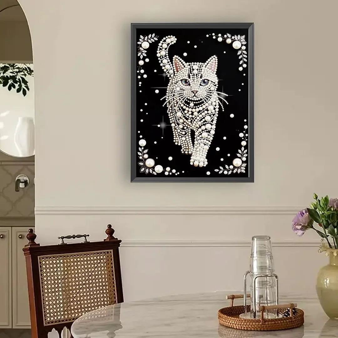 A framed piece of art featuring a cat silhouette outlined in white beads and pearls against a black background.