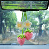 Handmade crochet strawberry mirror pendant hanging from a rearview car mirror.