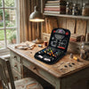 A compact travel sewing kit with various tools is displayed on a wooden table next to a window.