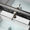 A modern faucet with a glass spout is shown over a white sink, featuring a stone tray for fast-drying water absorption.