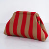 Pochette crochet rayée rouge et beige, pliée sur une surface blanche.