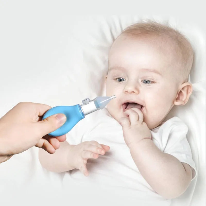 A baby is being gently aspirated from the nose using a blue nasal aspirator device.