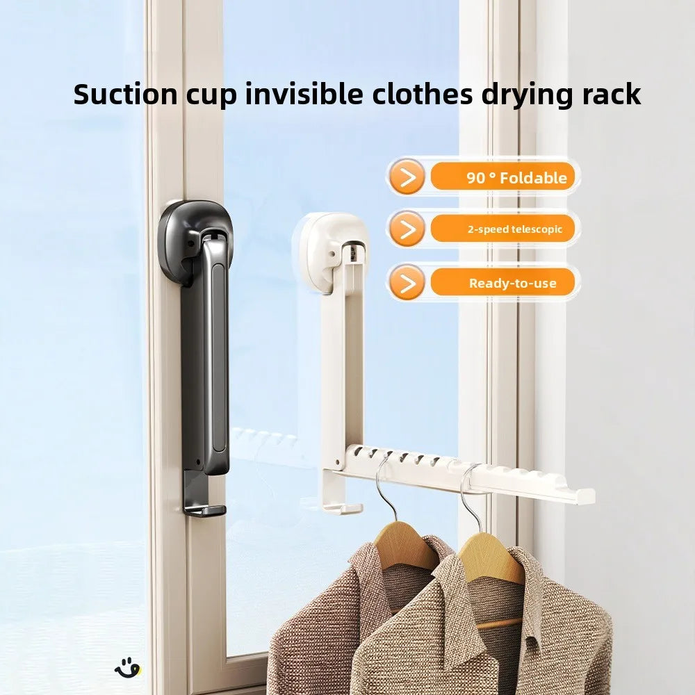 A white suction cup invisible clothes drying rack mounted on a window, holding clothes.