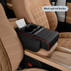 A black car armrest cushion with cup holders and storage is shown in a beige car interior.