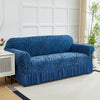 A deep blue jacquard sofa cover with a zebra stripe pattern and an elastic skirt displayed in a bright room.