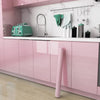 A pink kitchen cabinet with a marble backsplash featuring a faucet and various kitchen tools.