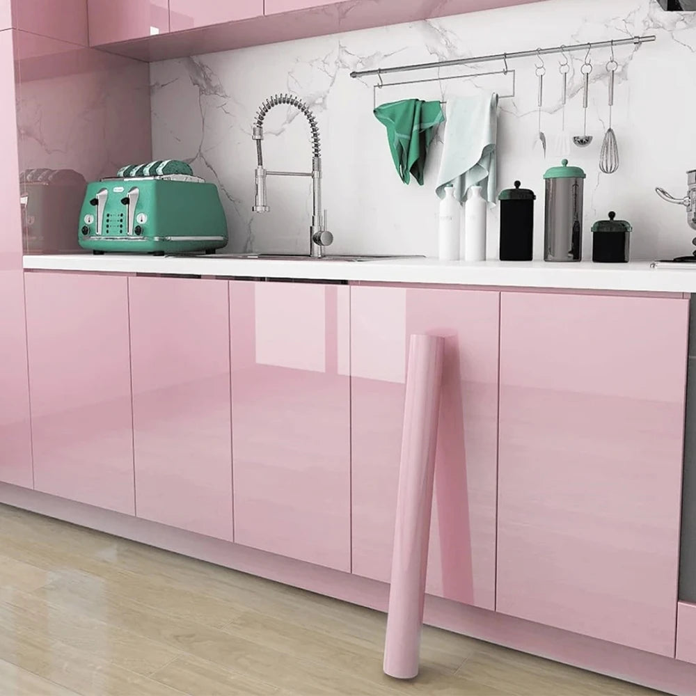 A pink kitchen cabinet with a marble backsplash featuring a faucet and various kitchen tools.