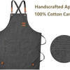 A dark gray handcrafted cotton canvas apron with cross-back straps and chest pockets.