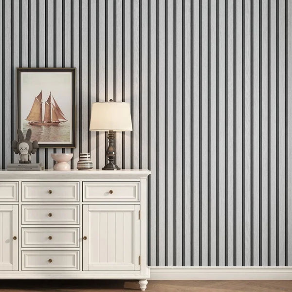 A white cabinet with drawers and a lamp is displayed against a gray striped wall.