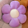 A purple and cream lifelike sunflower plush pillow with soft furry texture resting on a light-colored fabric.