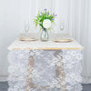 Vintage white embroidered floral lace table runner displayed on a table setting with a vase of greenery and white flowers.