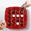 A hand is rotating a red Quadruple Chess board game with black and white pieces.