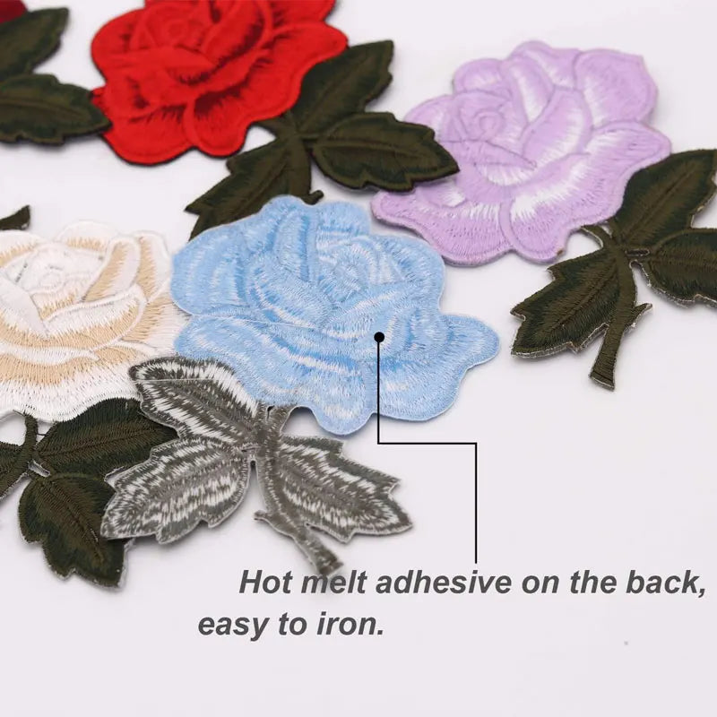 A collection of colorful rose and butterfly embroidered iron-on patches in various shades of pink, blue, and purple on a whit
