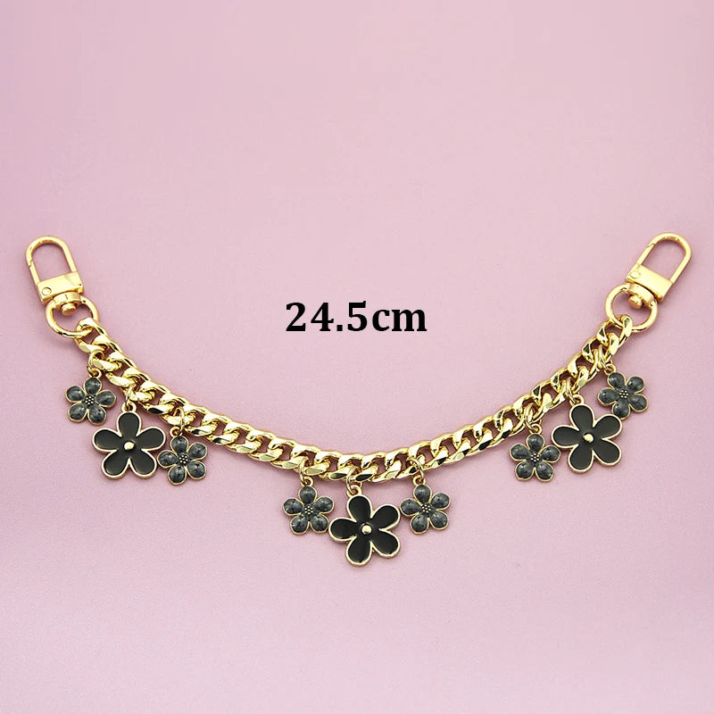 Gold chain phone strap featuring decorative black flower charms and a lobster clasp.