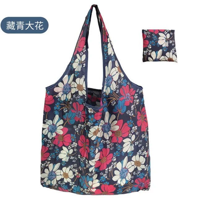 A navy blue reusable shopping tote bag featuring a floral pattern of pink, red, and white flowers.