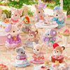 A collection of Sylvanian Families tea party baby figures and blind bag collectibles arranged on a table.