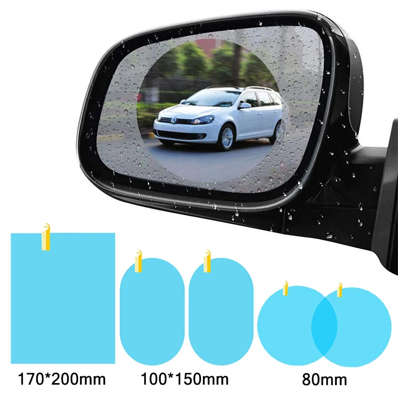A close-up view of a black car mirror with clear anti-fog and rain-repellent film applied, showing a blurred outdoor scene.