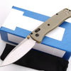 A compact folding knife with a light tan handle and stainless steel blade rests on a blue box.