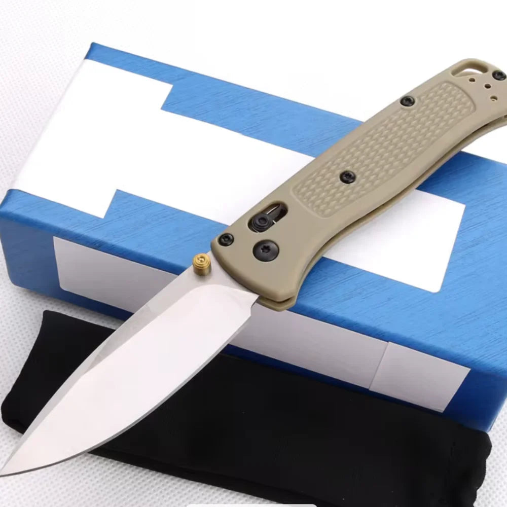 A compact folding knife with a light tan handle and stainless steel blade rests on a blue box.