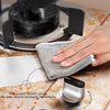 A hand is using a non-scratch scrub pad to clean a black cooking surface.