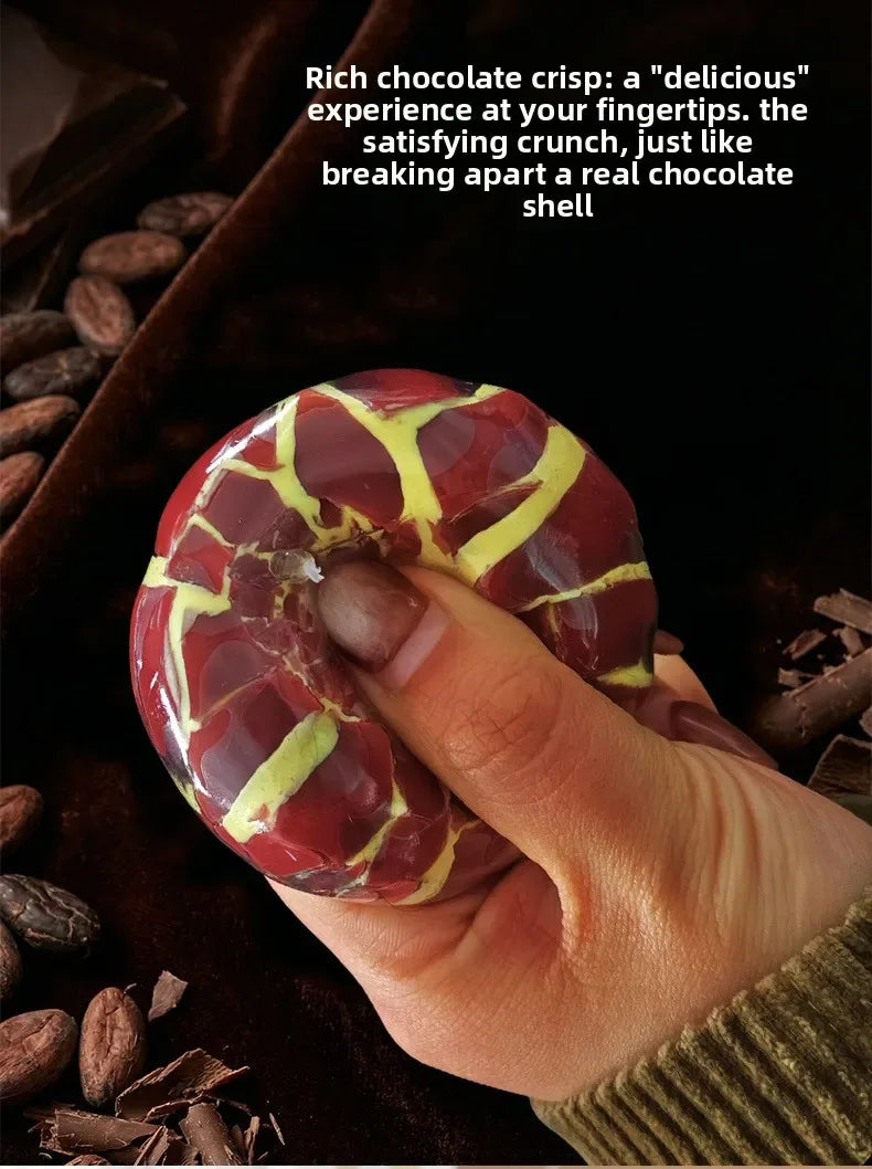 A hand holds a red and yellow chocolate crisp, showing its texture and satisfying break apart.