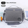 A gray insulated lunch bag with a strap is shown on a white surface.