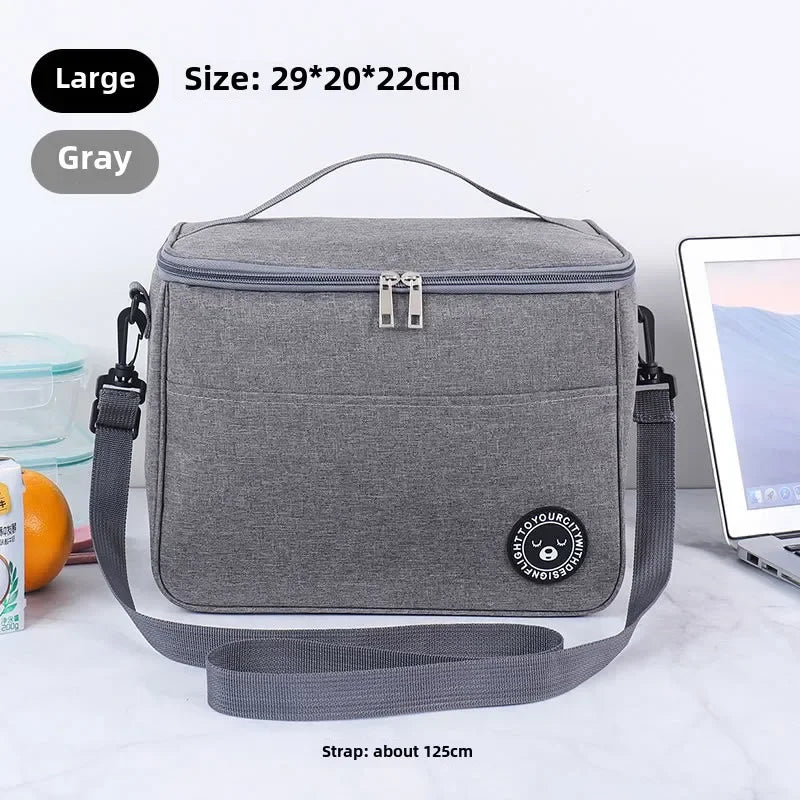A gray insulated lunch bag with a strap is shown on a white surface.