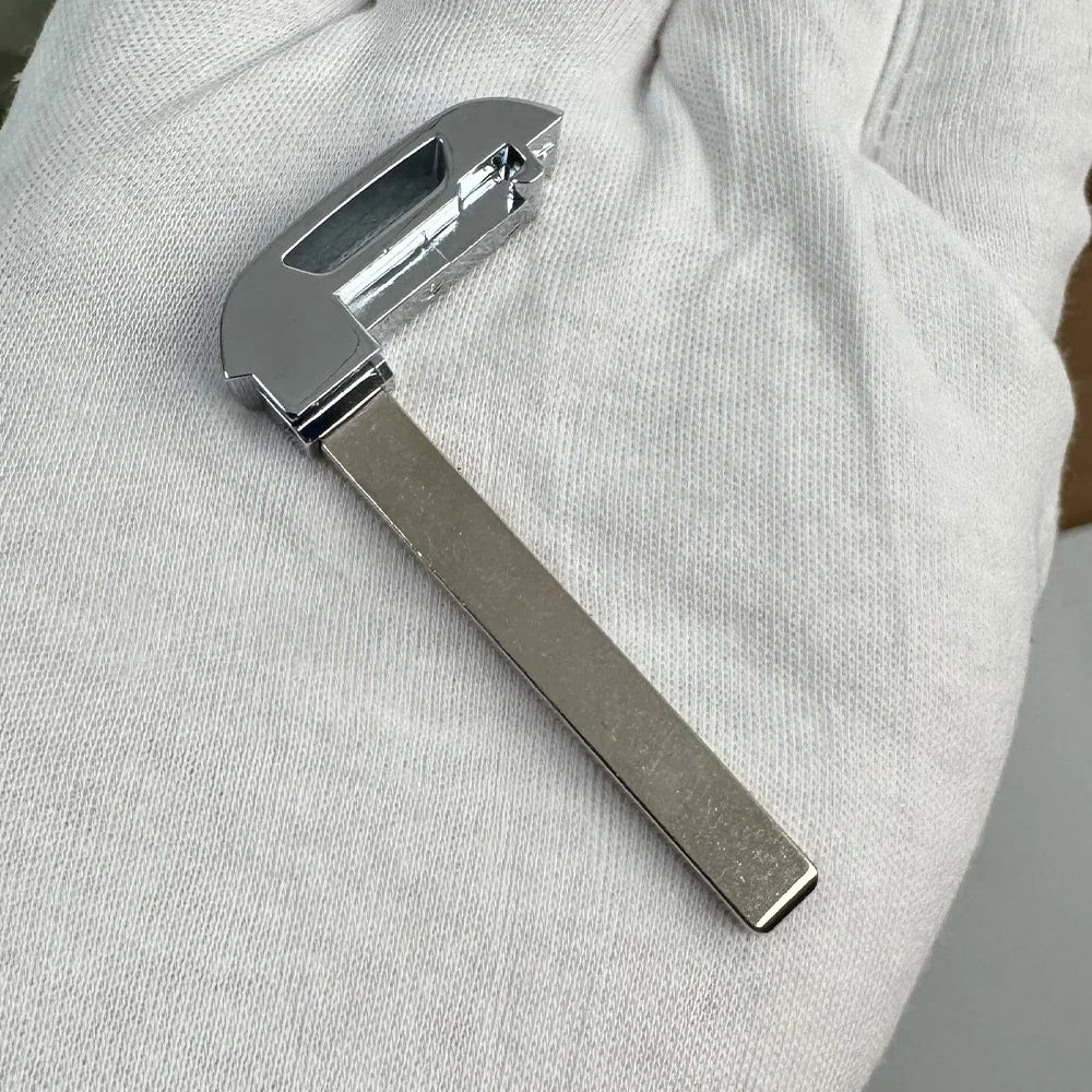 A silver replacement remote key for a Chevrolet or GMC vehicle is shown held in a hand.