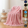 A pink brushed flannel throw blanket draped over a chair in a bright room.