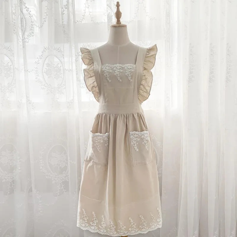 A cream ruffled cotton linen kitchen apron with lace trim displayed on a mannequin.