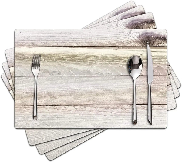 Eine Stapel helle Holz-Platzsets mit Besteck darauf.