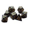 A set of black polyhedral dice with gold dragon embellishments scattered on a white surface.