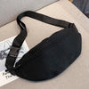 Black linen waist pack with a black strap lying on a beige surface.