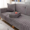 Gray quilted velvet sofa cushion covers displayed on a sofa with a white cabinet in a bright room.