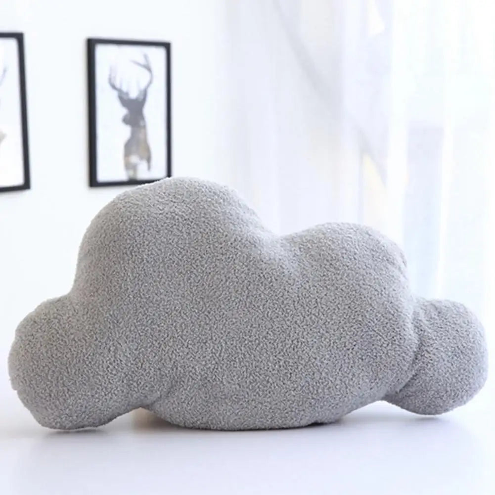 A soft gray cloud-shaped plush throw pillow resting on a white surface.