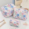 A light pink and blue patchwork quilted makeup bag next to a butter-themed book.
