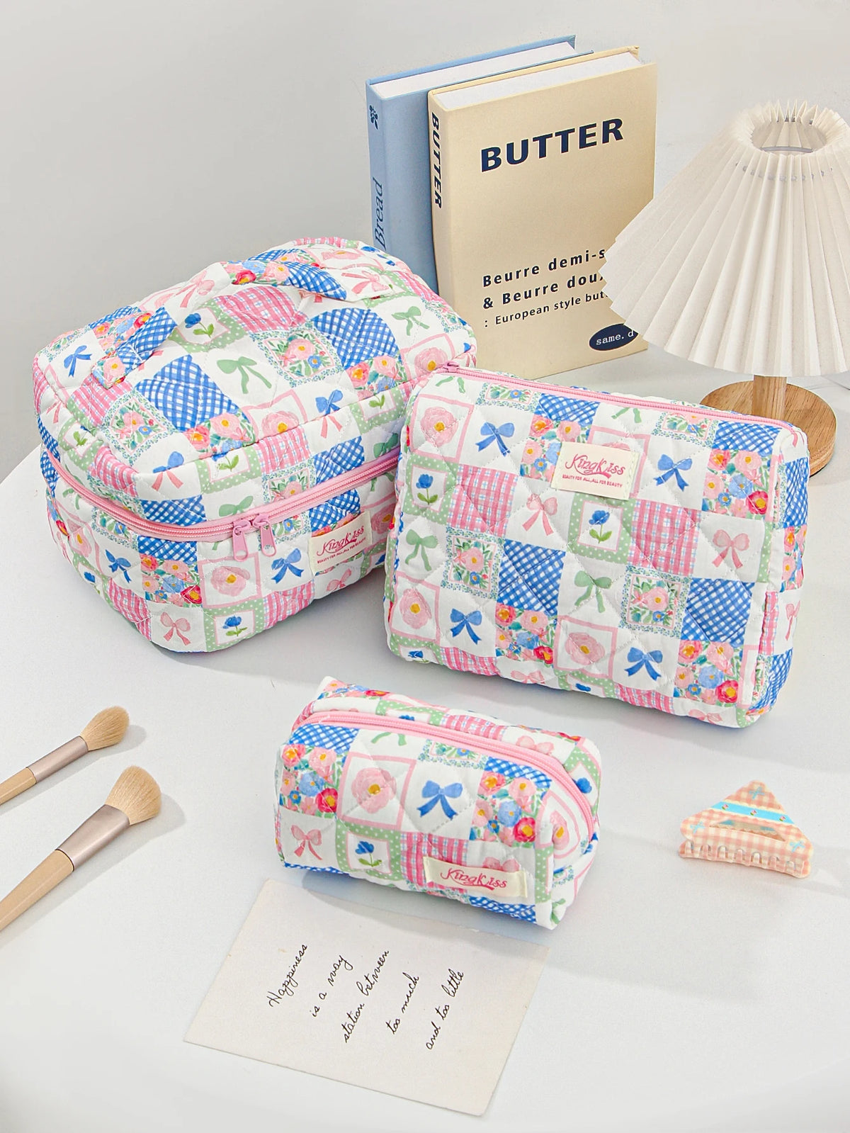 A light pink and blue patchwork quilted makeup bag next to a butter-themed book.