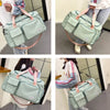 A light mint green waterproof travel duffle bag with a shoe compartment being carried by a person.