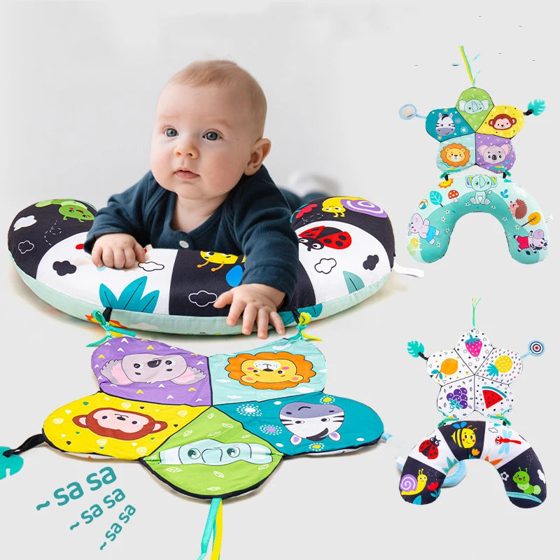 A baby is lying on a high contrast tummy time pillow featuring colorful shapes and animals.