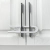 A close-up of adjustable U-shaped cabinet locks installed on a white wooden door frame.