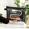 A hand holds a black canvas charger and cables storage pouch with white text on a white surface.