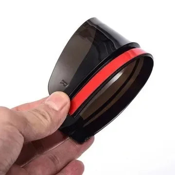 A close-up view of a black carbon fiber car side mirror rain and sun visor being held by a hand.