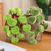 A potted plant made of soft green faux leaves resembling a pothos, displayed in a clear glass container.