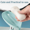 A hand holds a white leaf-shaped suction cup soap dish with a self-draining tray in a light blue bowl.