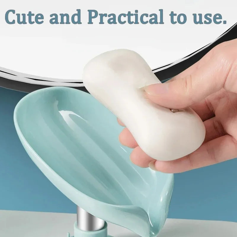 A hand holds a white leaf-shaped suction cup soap dish with a self-draining tray in a light blue bowl.