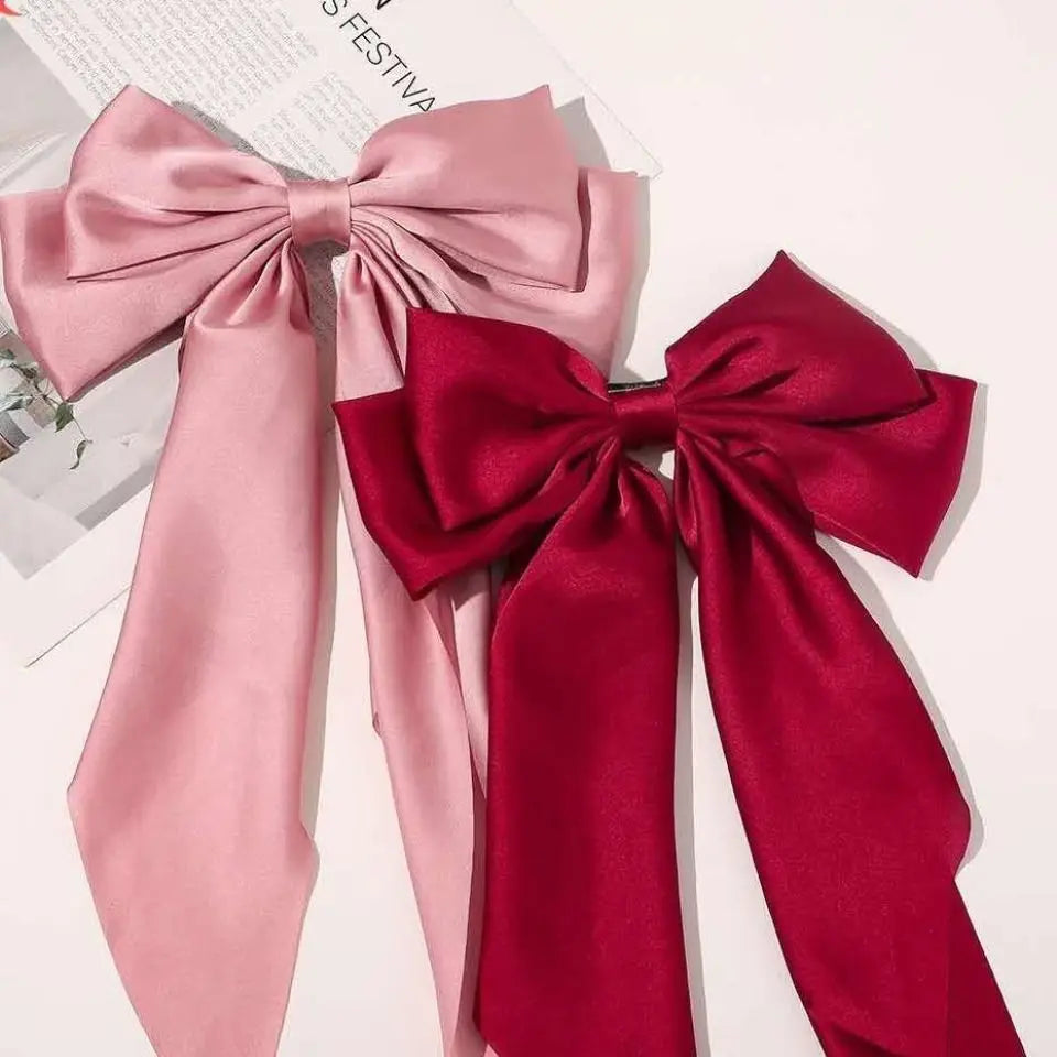 A set of pink and red silk bows used as hair accessories for ponytails.